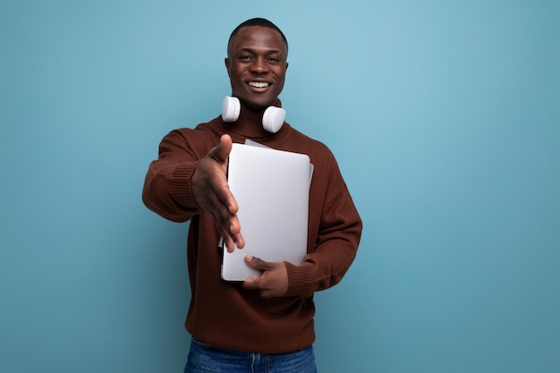 Successful young african male freelancer with a laptop in his hands on the background with copy