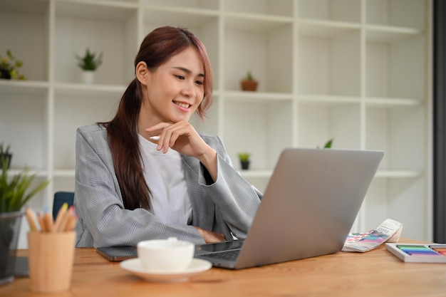 Successful young Asian businesswoman working at her office desk using laptop