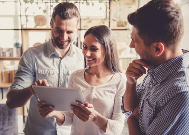 I giovani imprenditori di successo utilizzano un tablet digitale per condividere idee e sorridere mentre lavorano in ufficio