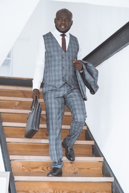 Successful young businessman african american guy descends stairs to work in morning concept of luxu...