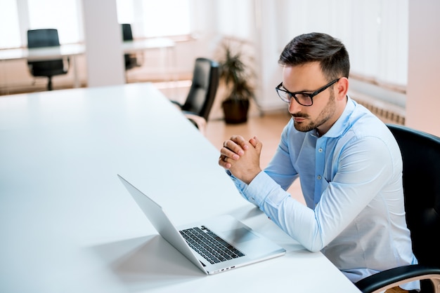 Riuscito giovane uomo d'affari che lavora al computer portatile sul posto di lavoro