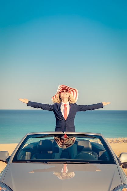 Successful young businesswoman on the beach Woman standing in the cabriolet classic car