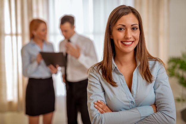 Successful young businesswoman standing proudly in the office and looking at the camera.