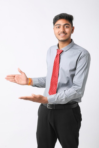 Успешный молодой индийский деловой человек позирует на белом фоне.