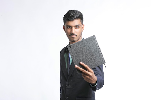 Successful Young Indian businessman or employee wearing Suit and cheaking dairy on white background.