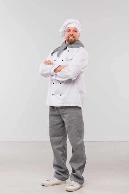 Successful young male chef with his arms crossed by chest looking at you while standing in isolation