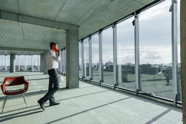 Successful young man in formal wear is working indoors on the construction