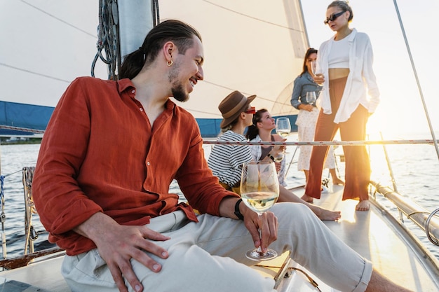 Successful young man relaxing on his sailboat with girl friends during sailing in sea