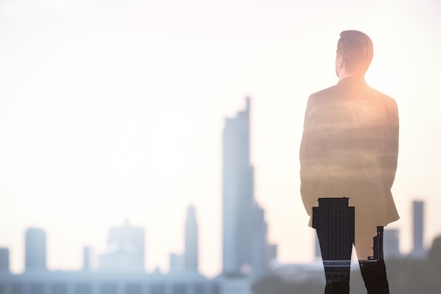 Successful young man silhouette on blurry city background with mock up city view Future and financial freedom concept Double exposure