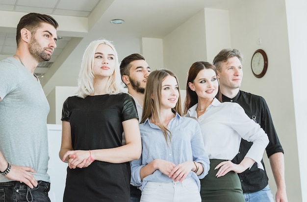 Giovani di successo che stanno insieme e guardano il loro brillante futuro al chiuso