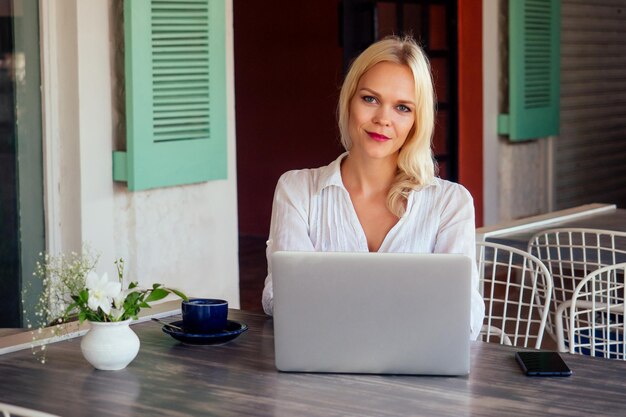 Successful young woman chatting on the phone during her lunch break.Candid image of a businesswoman talking on the phone in a summer outdoors cafe