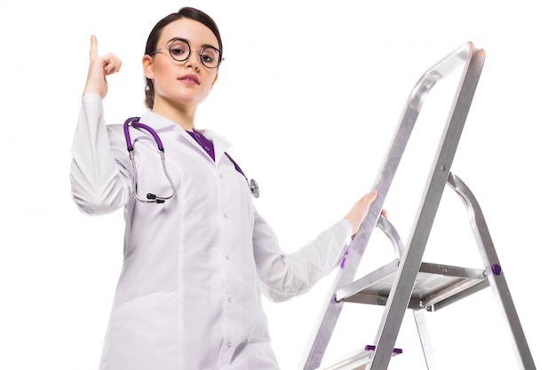 Successful young woman doctor with stethoscope climbing ladder of success in white uniform