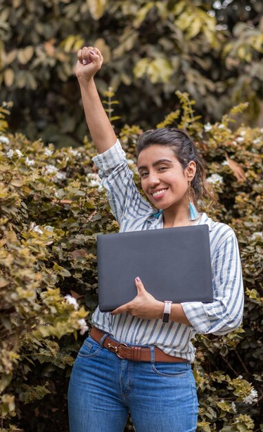 Successful young woman holding her fist in the air smiling