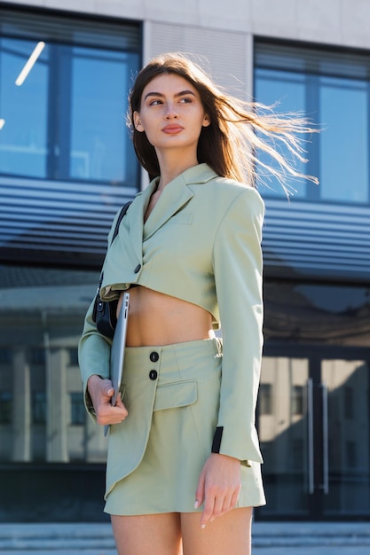 A successful young woman in a stylish suit with her hair fluttering in the wind poses outside Business Portrait