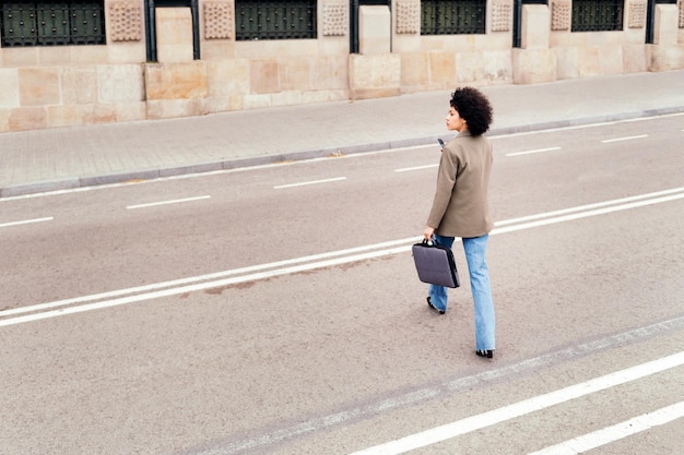 Successful young woman walking across the street