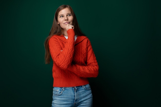 Successful young woman wearing a red sweater on a green background