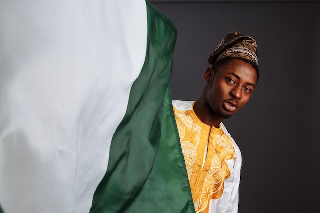 Succesvolle Afrikaanse man winnaar voordat hij met de vlag van Nigeria zwaaide Glimlachend en naar de camera kijkend