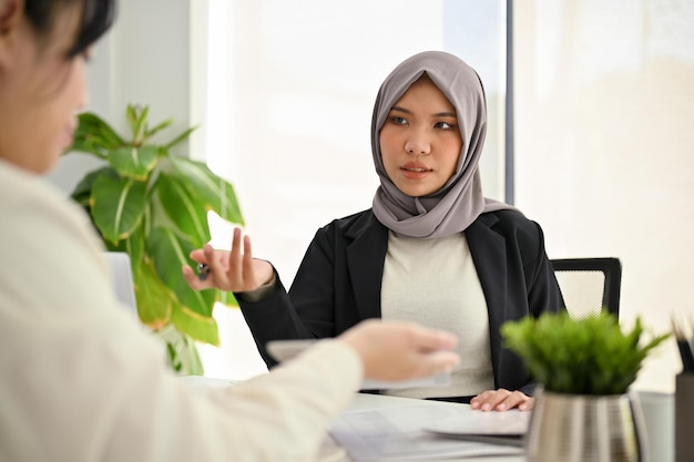 Succesvolle Aziatische moslim zakenvrouw of vrouwelijke baas in de ontmoeting met haar team