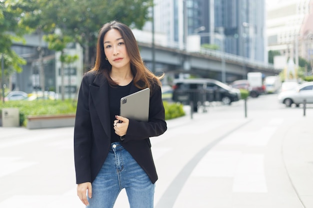 Succesvolle aziatische zakenvrouw draagt een zwart pak met een tablet die op straat loopt vrouw freelancer levensstijl menselijke stedelijke. kopieer ruimtegebruik voor tekstwoord.