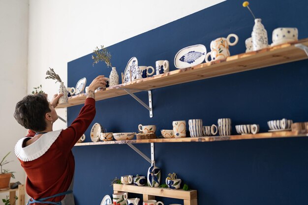 Succesvolle eigenaar van keramiekatelier regelt vitrine met afgewerkte producten te koop