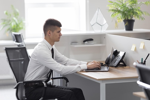 Succesvolle gelukkige zakenman zit aan een bureau op kantoor en gebruikt een laptop