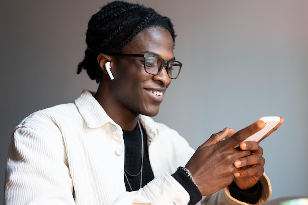 Succesvolle glimlachende Afro-Amerikaanse man met telefoon gebruikt vermakelijke mobiele apps of sociale media