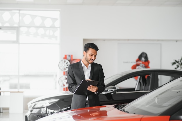 Succesvolle Indiase zakenman in een autodealer verkoop van voertuigen aan klanten