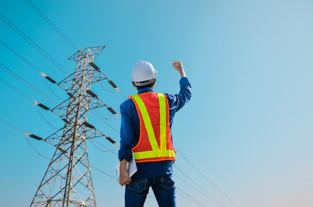 Succesvolle ingenieurs staan tegen hoogspanningspalen op een blauwe achtergrond