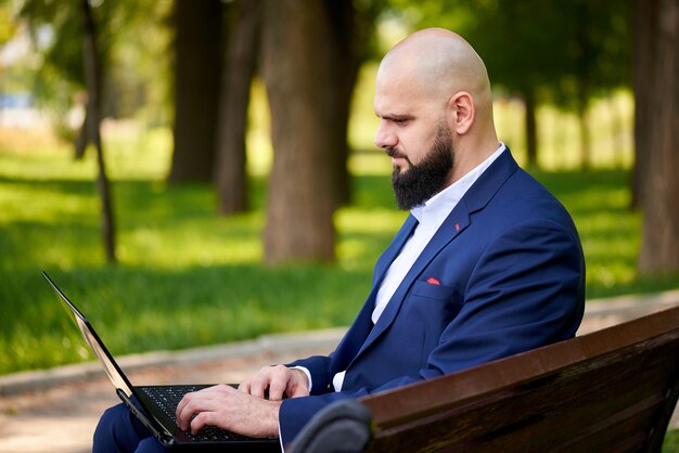 Succesvolle jonge man met laptop in het park.