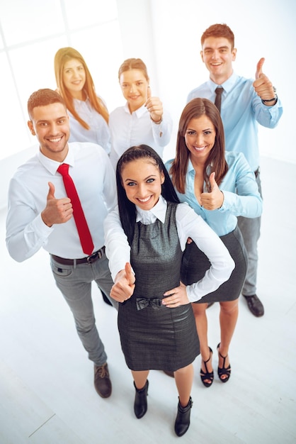 Succesvolle jonge zakenvrouw staat trots met haar jonge business team en kijkt naar de camera.