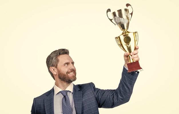 Succesvolle man in pak houdt kampioen cup s zakelijke beloning geïsoleerd op wit succes