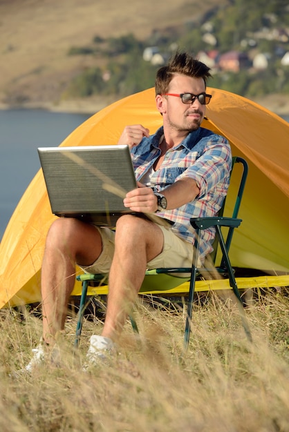 Succesvolle man met laptop zittend in klapstoel.