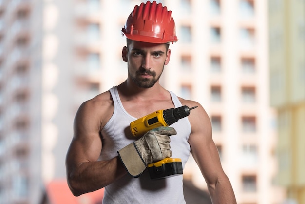 Foto succesvolle mannelijke architect op een bouwplaats met boor