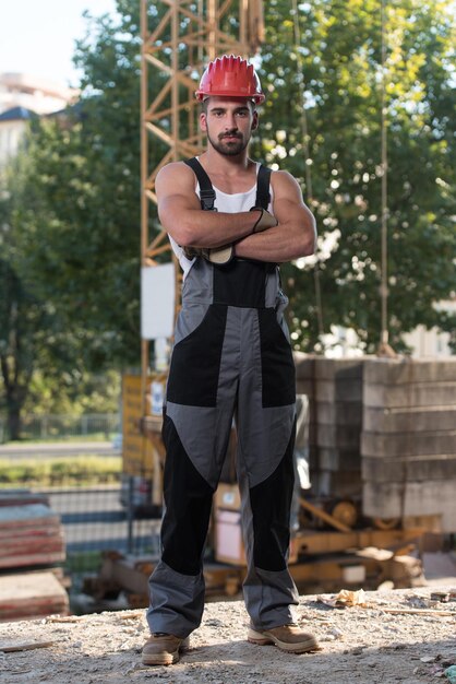 Foto succesvolle mannelijke architect op een bouwplaats met gekruiste armen