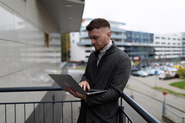 Succesvolle mannelijke zakenman die aan laptop buiten het kantoor werkt