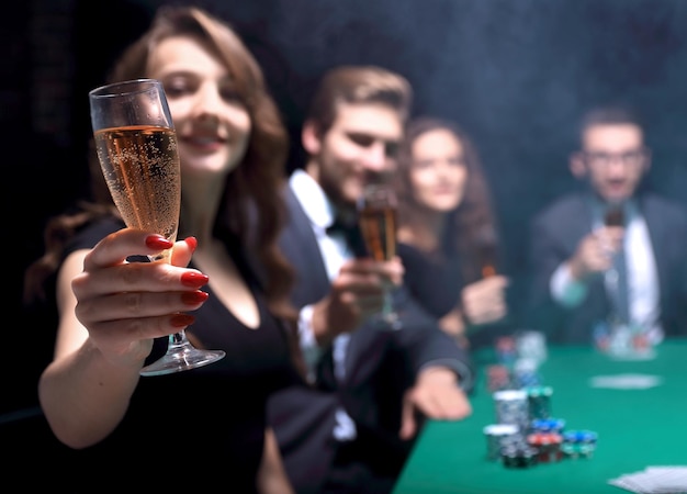 Succesvolle modevrouw met glazen wijn zittend aan een tafel in een casino