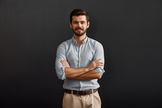 Succesvolle projectmanager vrolijke en jonge bebaarde man die met een glimlach naar de camera kijkt en houdt