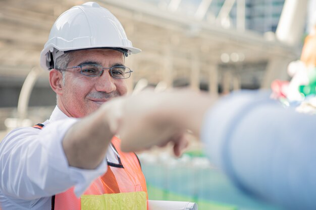 Succesvolle senior ingenieurs stoten hun vuisten met collega's.