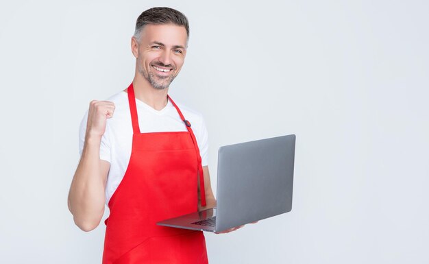 Succesvolle volwassen man in schort chatten op computer