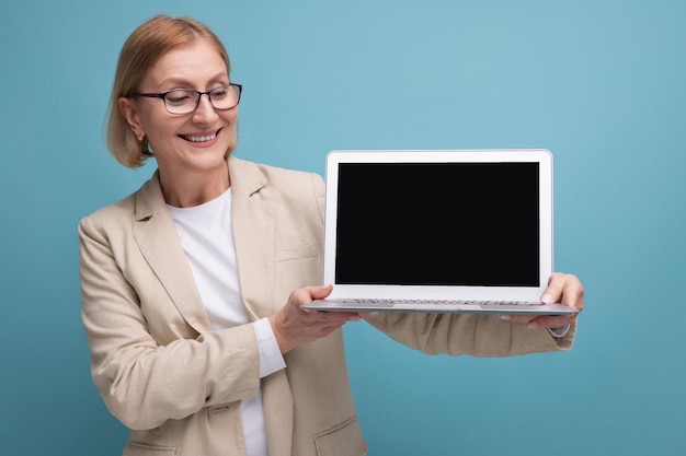 Succesvolle vrouw van middelbare leeftijd in jas met laptop om aan studioachtergrond te werken met kopieerruimte