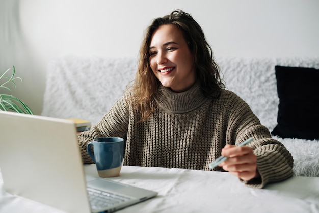 Succesvolle vrouwelijke ceo-multitasking aan keukentafel tijdens videoconferentie met partners die gebruik maken van