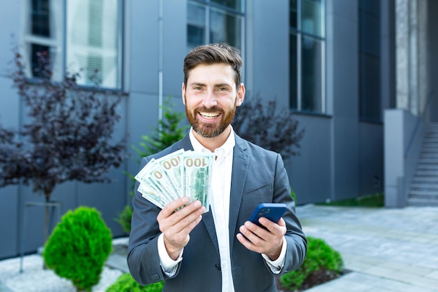 Succesvolle winnaar van de man heeft dollars in contanten, verheugt zich over het winnen via de telefoon, zakenman verheugt zich