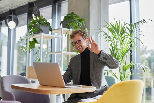 Succesvolle zakenman begroet zijn gesprekspartner tijdens online conferentie op laptop via videolink