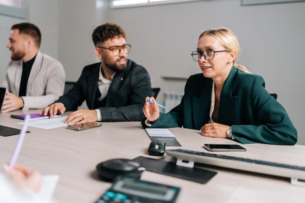 Succesvolle zakenvrouw baas in pak die praat met zakenmensen collega's of partners die aan tafel zitten Vrouwelijke leider die het werk bespreekt tijdens een teamvergadering