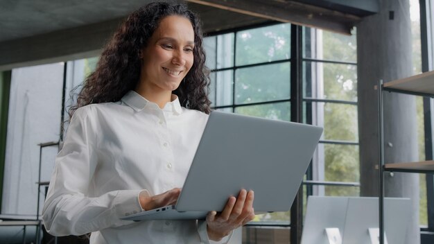 Succesvolle zakenvrouw die in een modern kantoor werkt, op een laptop schrijft, op afstand communiceert met een klant