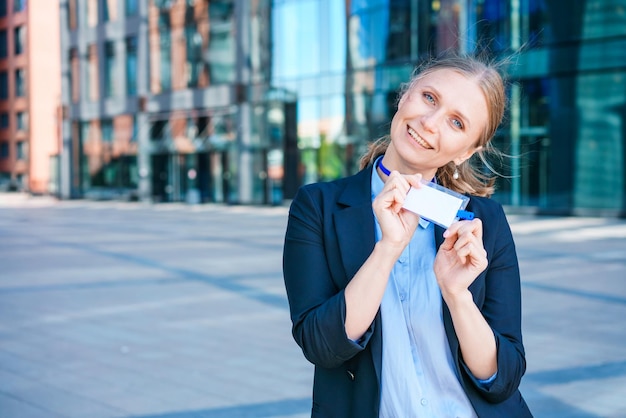 Succesvolle zakenvrouw in blauw pak en overhemd houdt badge in haar hand