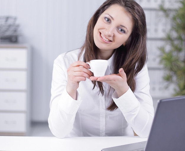 Succesvolle zakenvrouw met koffiekopje aan haar bureau