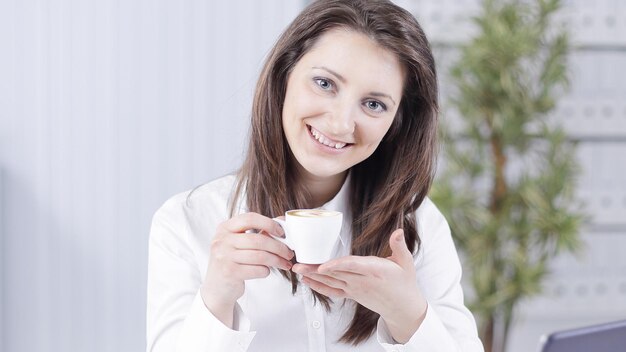 Succesvolle zakenvrouw met koffiekopje aan haar bureau