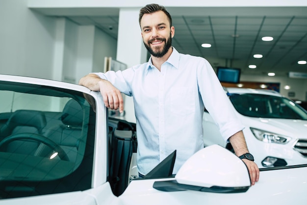 Successo bell'uomo barbuto che compra una nuova auto sportiva in concessionaria