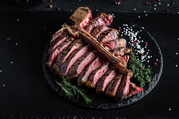 Succulent grilled large t-bone steak garnished on cutting board.